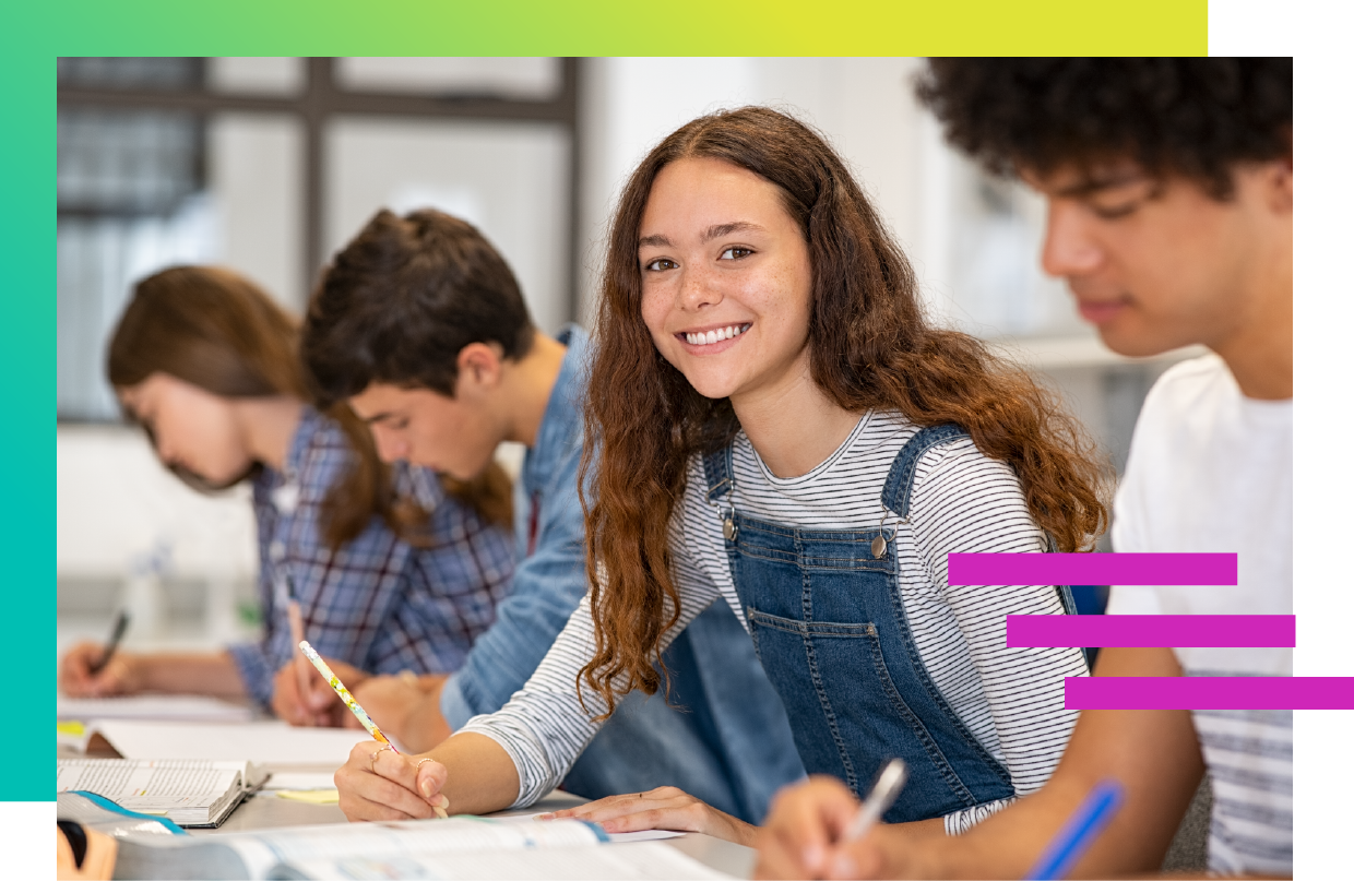 A row of students writing in school with one girl looking up and smiling