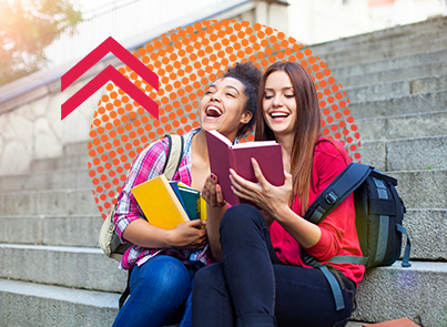 Two high school students reading books out loud and smiling on school steps