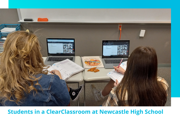 Two students writing in MATHbook in front of laptops in a ClearClassroom, a hybrid virtual instruction for math, at Newcastle High School, Wyoming