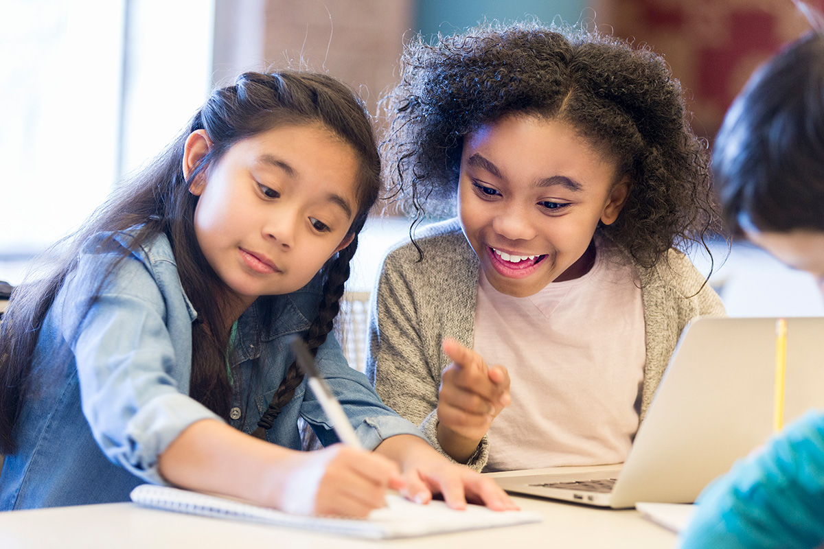 two girls confer over an assignment